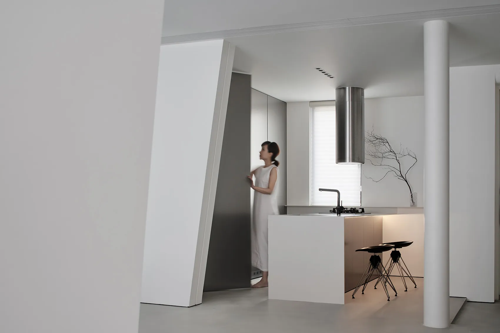 Modern, minimalist kitchen with white concrete surfaces, stainless steel appliances, and a sleek design.
