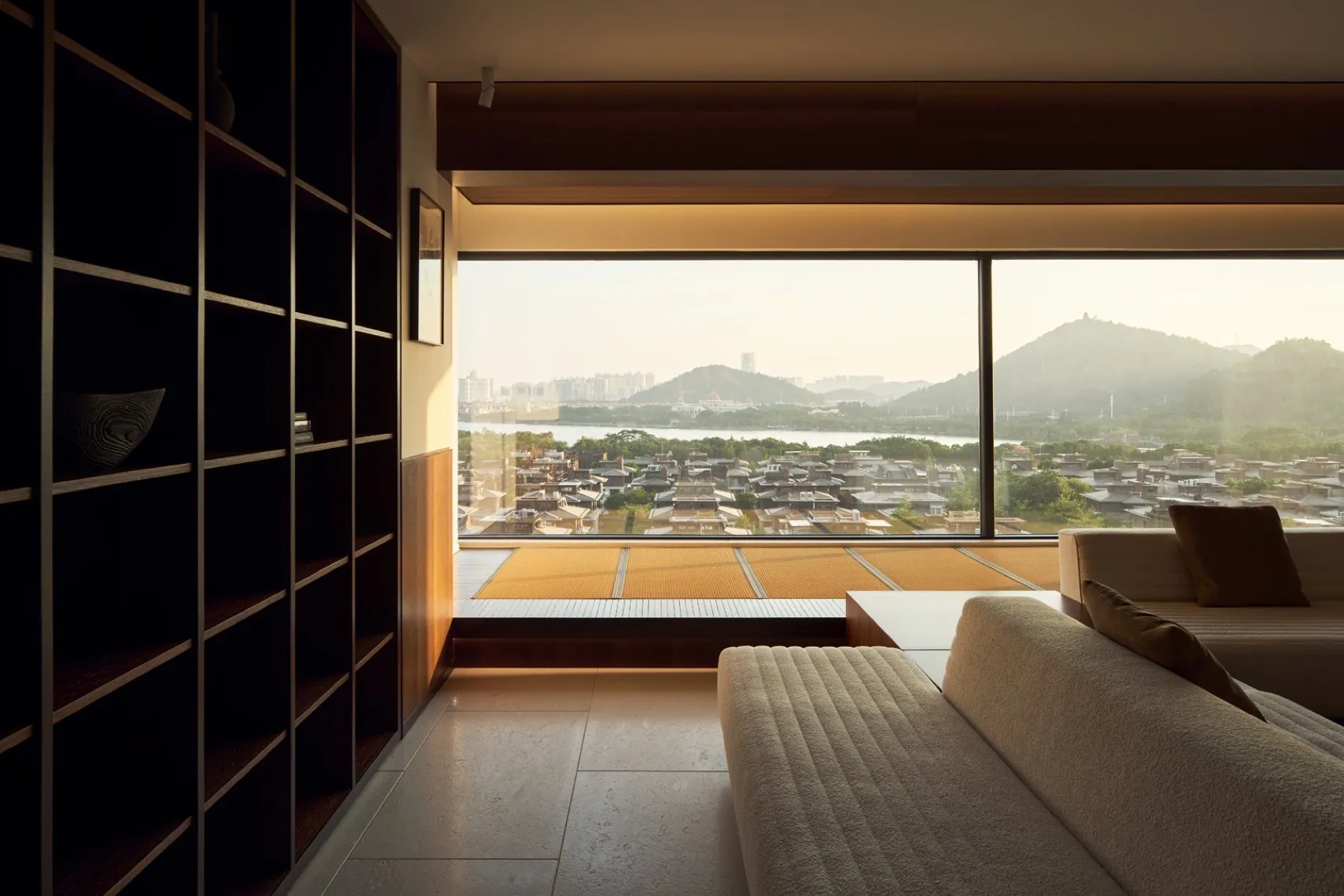 Modern living room featuring a glass window, wooden flooring, and upholstered furniture.