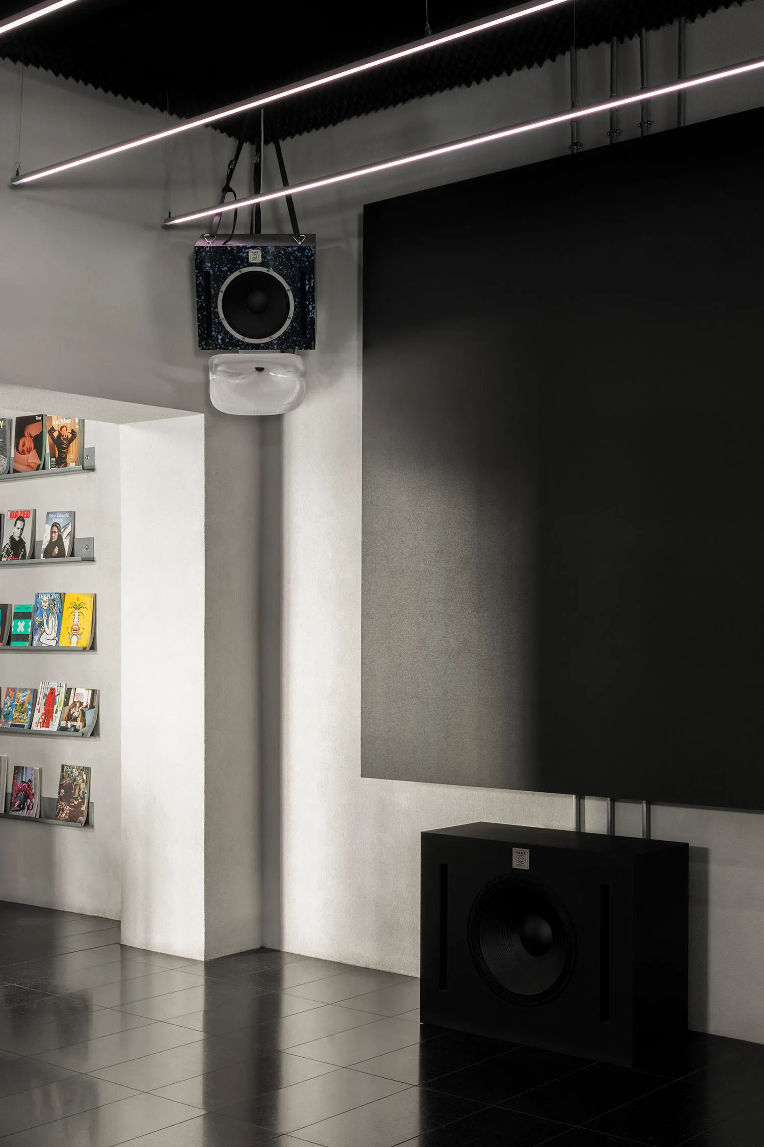 Cozy study with a large black speaker, multiple books, and a mounted TV in a modern and minimalist interior