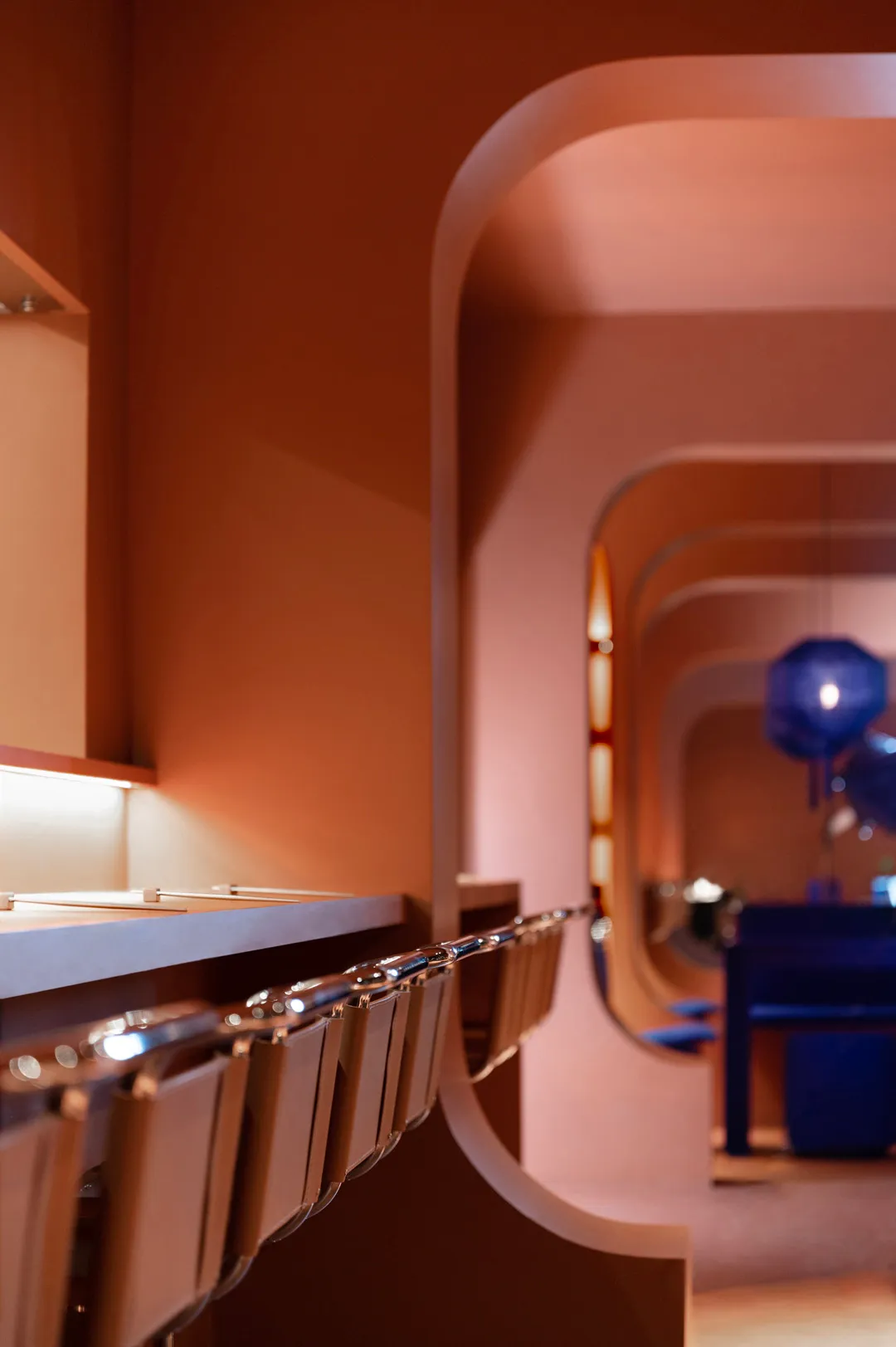 A modern bathroom with pink walls, multiple toilets, and seating areas, featuring clean lines and a focus on functionality and comfort