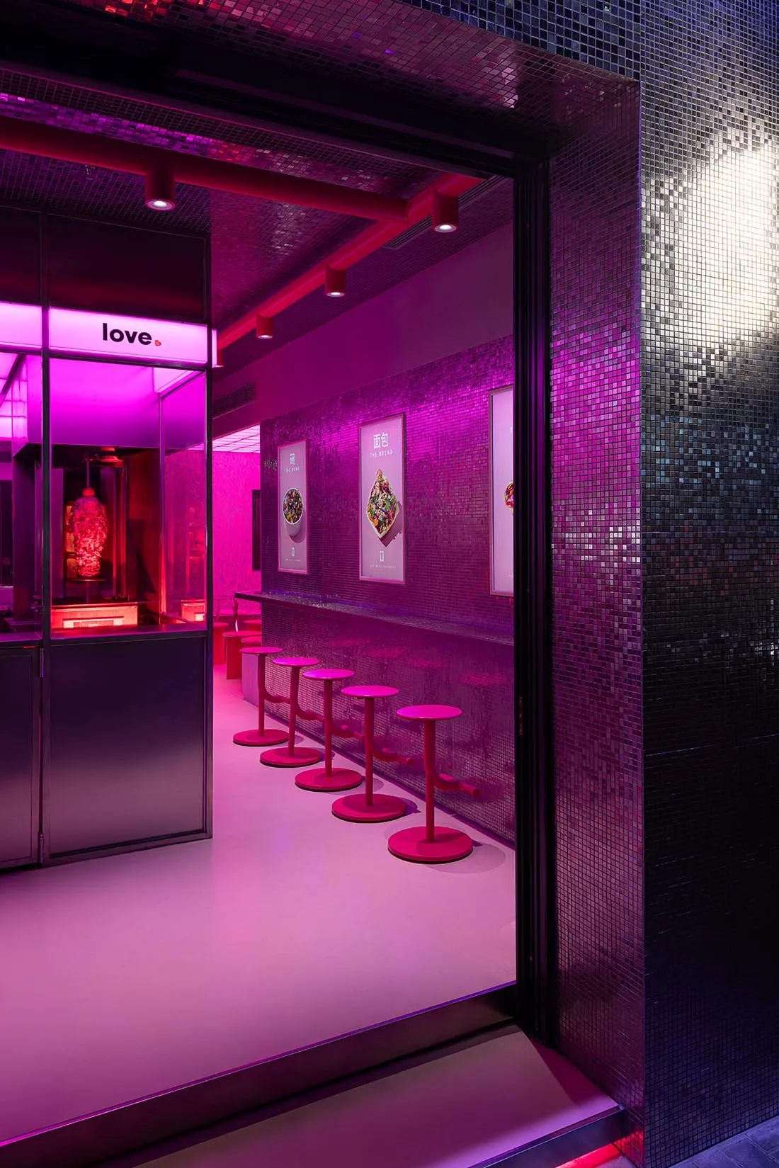 A restaurant interior with pink and purple accents, various chairs, and advertisements on the walls, creating a welcoming atmosphere