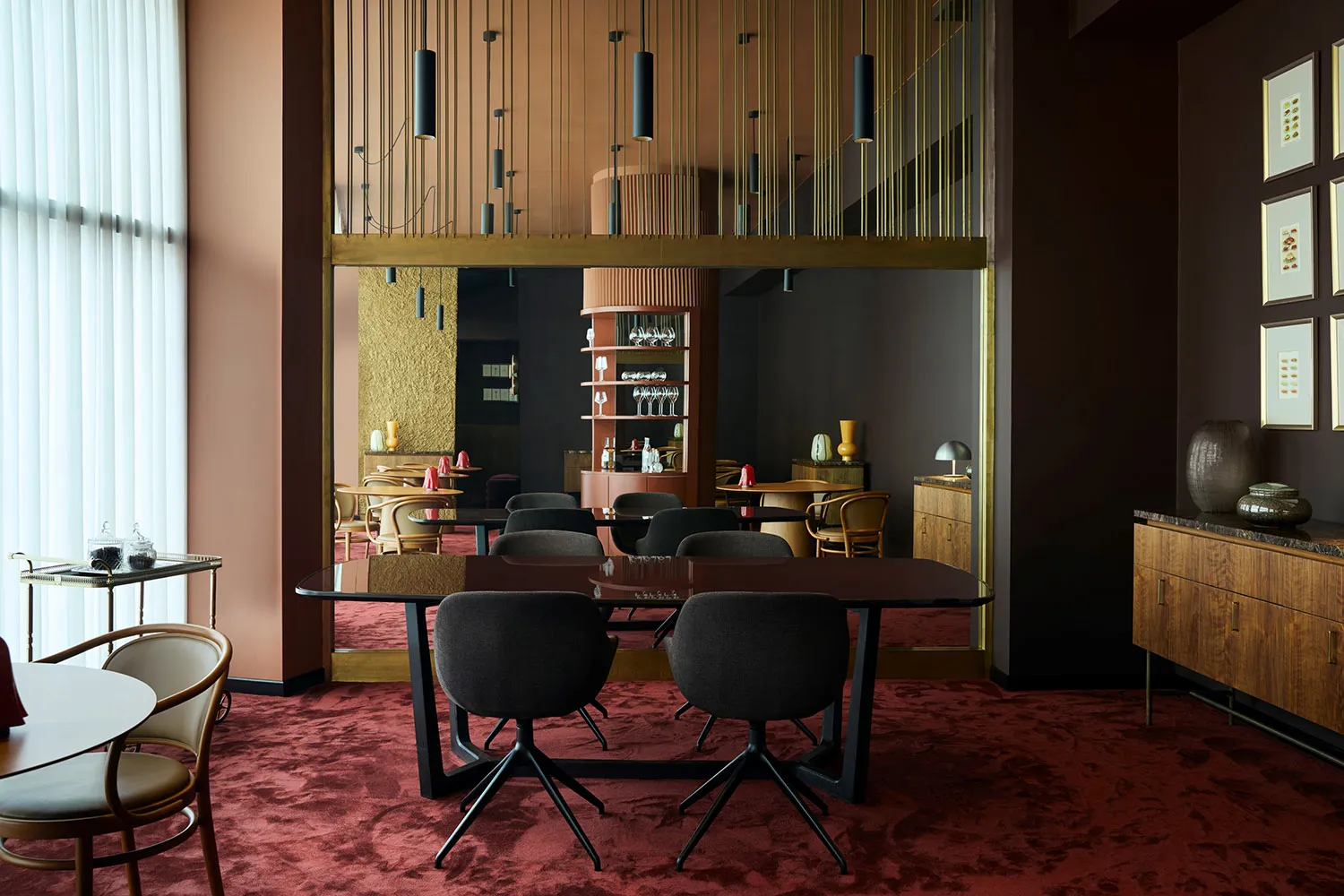 A modern cafe with a large wooden table surrounded by black chairs in a comfortable seating arrangement