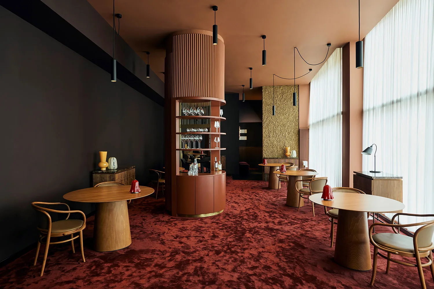 A restaurant interior with red carpet, tables, chairs, wine glasses, and decorative vases creating a warm and inviting atmosphere