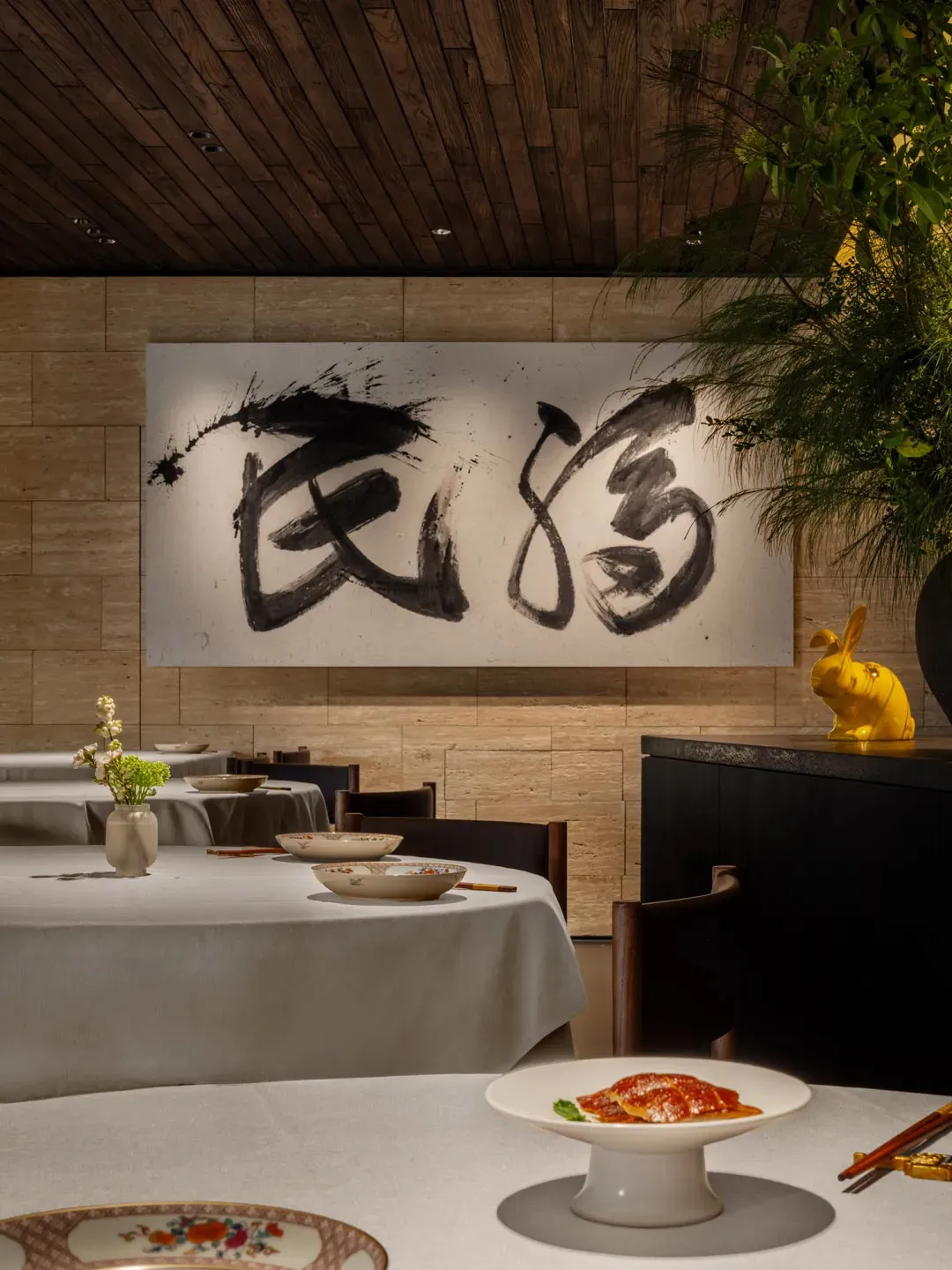 Cozy Asian restaurant interior with dining tables, chairs, artwork on the walls, and vases on the tables