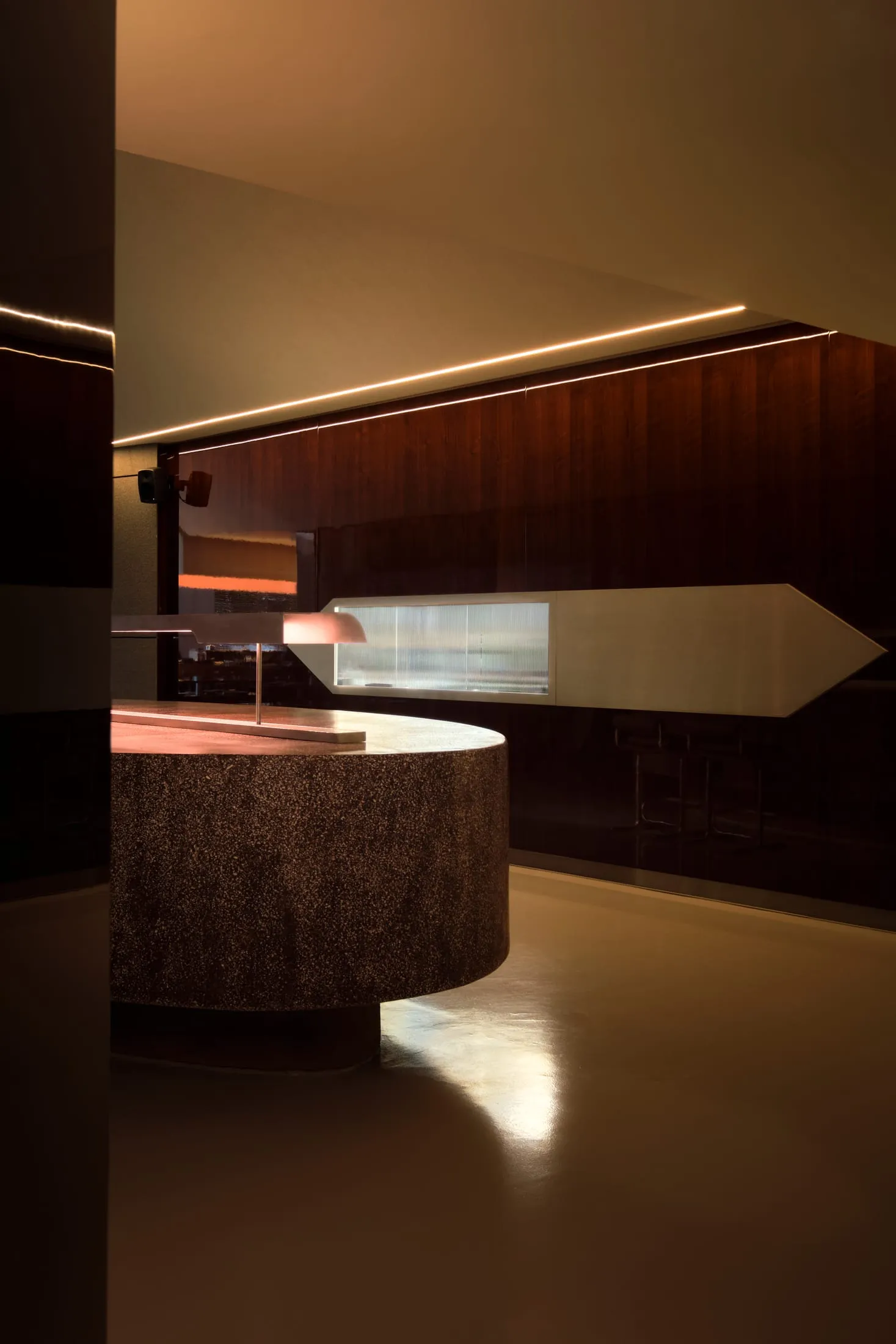 Modern bar area with a circular countertop, two chairs, and a lamp, set in a stylish and functional space