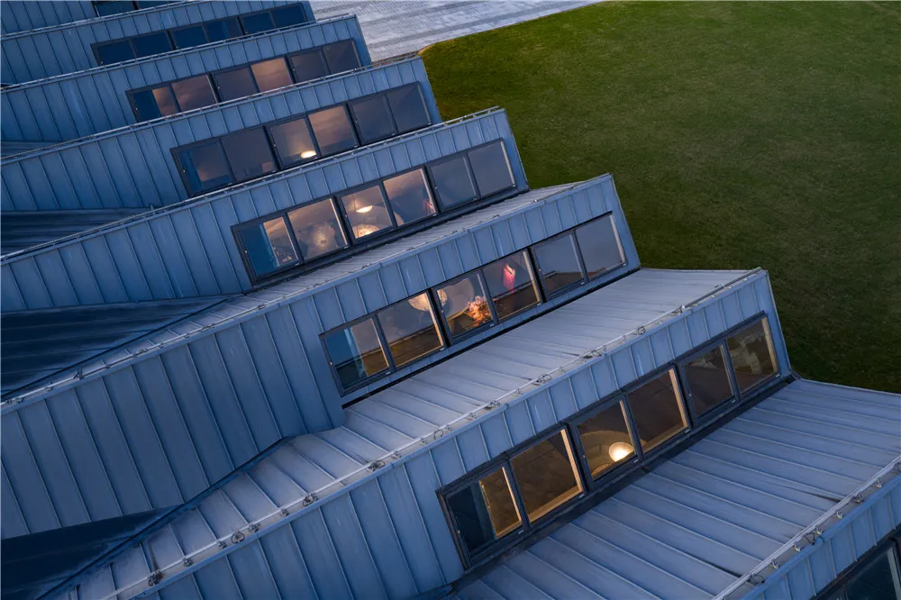 A modern urban building with blue roofs and windows, featuring metal cladding and a sophisticated design