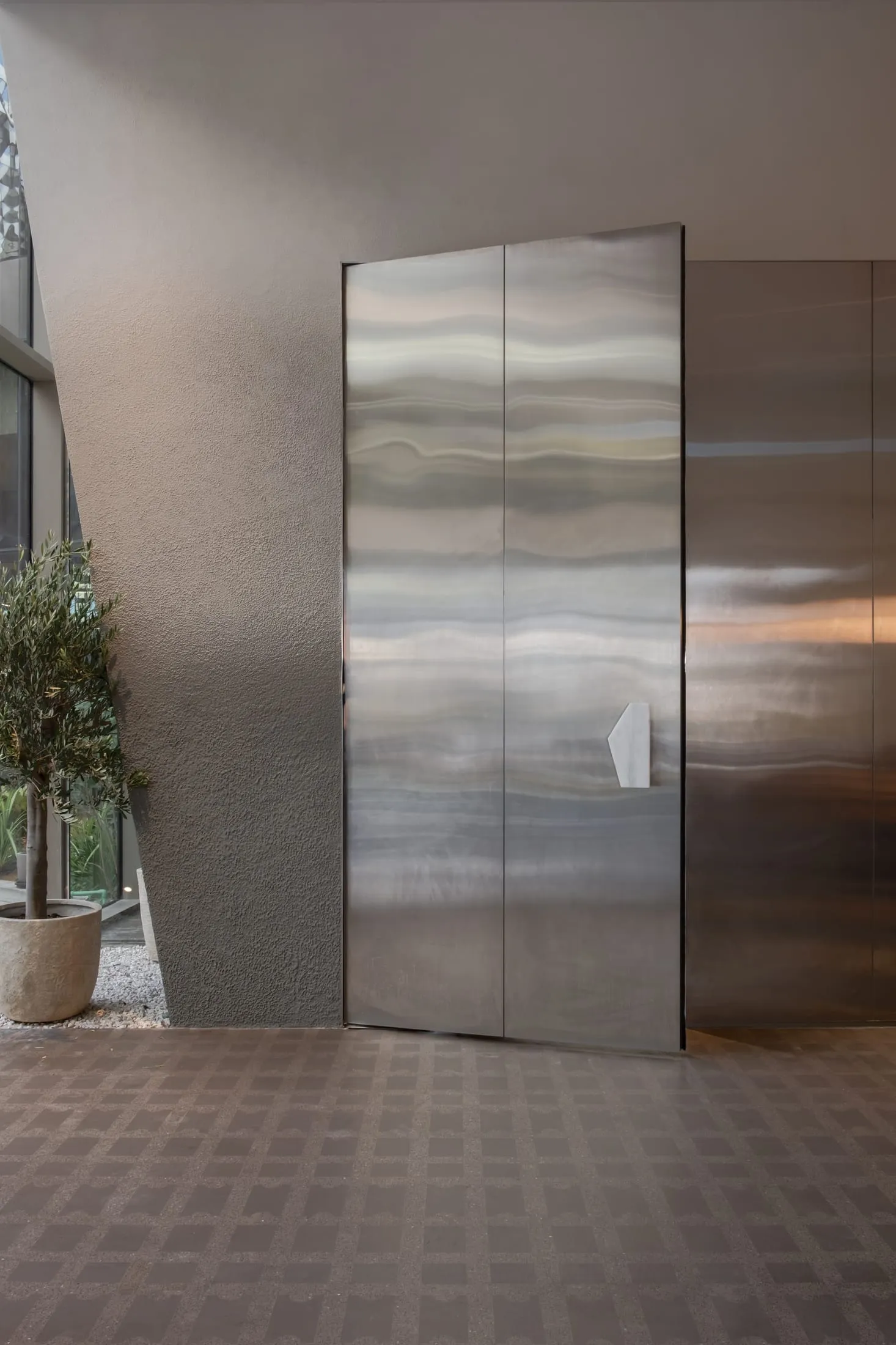A modern metal door in a contemporary urban setting, open to reveal a hallway beyond