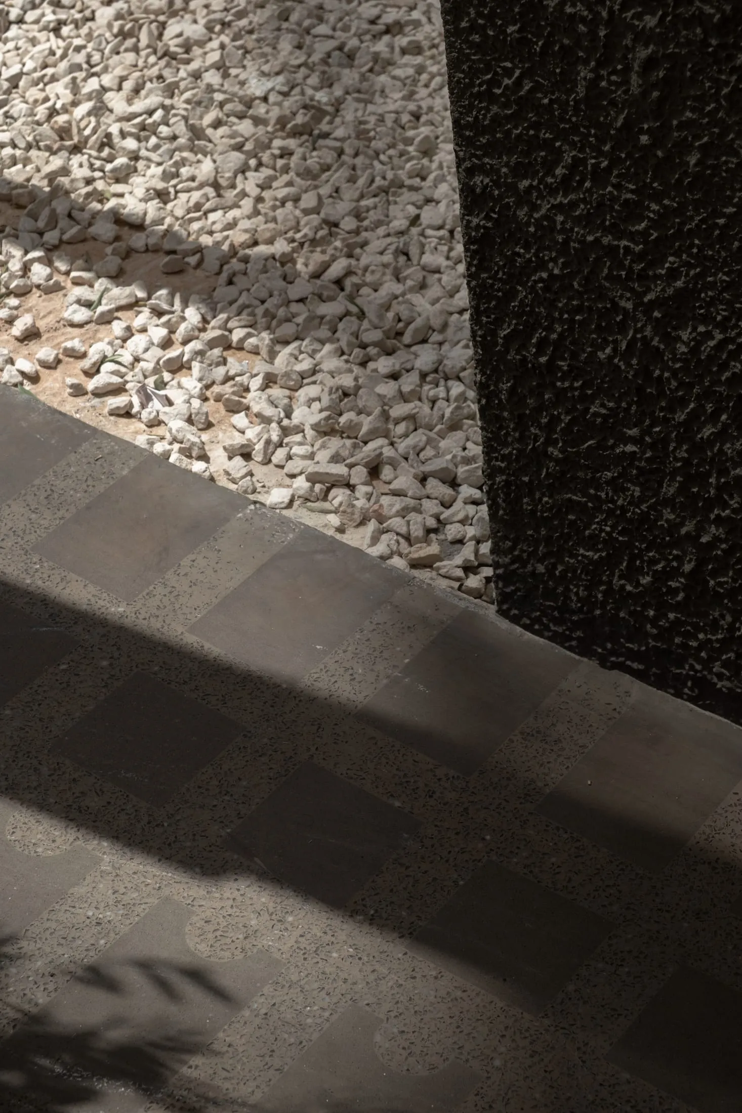 A hallway with a stone floor and scattered rocks, creating a natural and rustic ambiance with depth and contrast from the lighting
