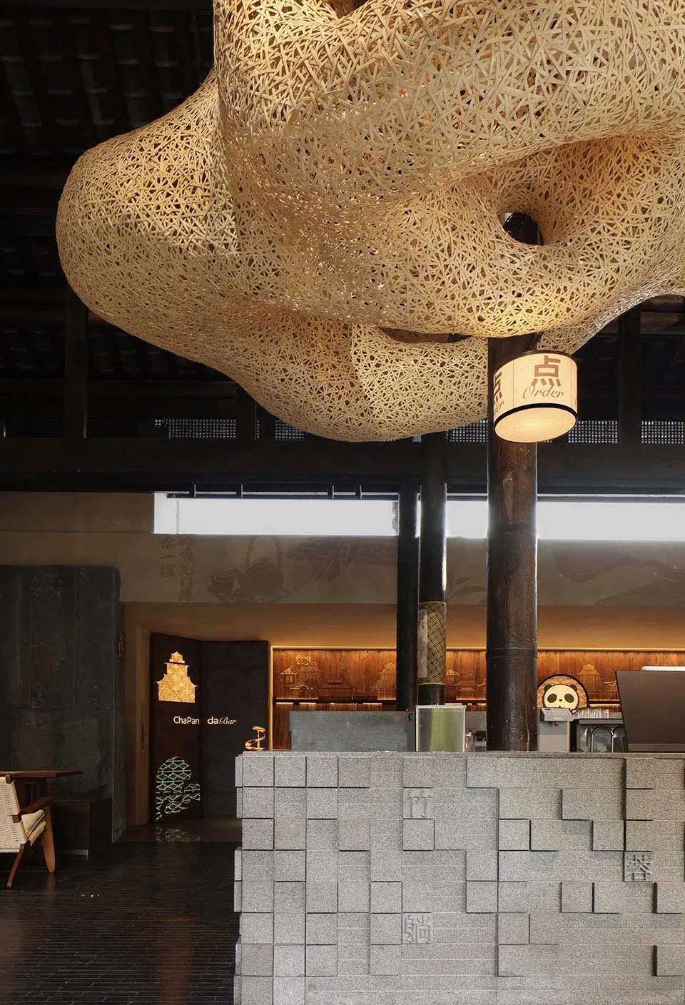 A creative interior design showroom featuring a large wooden and metal sculpture hanging from the ceiling, surrounded by smaller sculptures, furniture, and decorative pieces