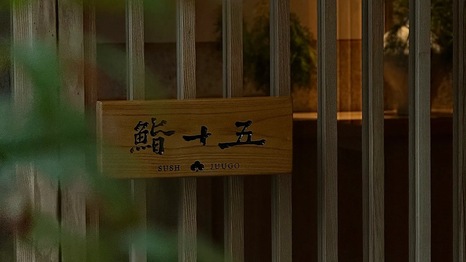 An Asian restaurant with wooden walls, a sign reading Sushi, and potted plants adding to the inviting and comfortable atmosphere