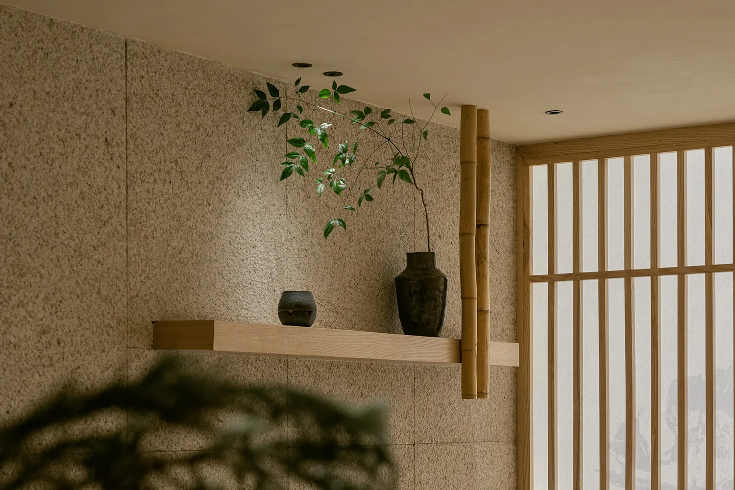 Cozy interior space with a wooden shelf displaying decorative vases and a potted plant, creating a warm and inviting atmosphere