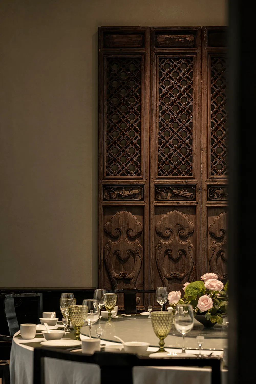 Ornate wooden door with intricate carvings, surrounded by wine glasses and cups in a sophisticated dining area