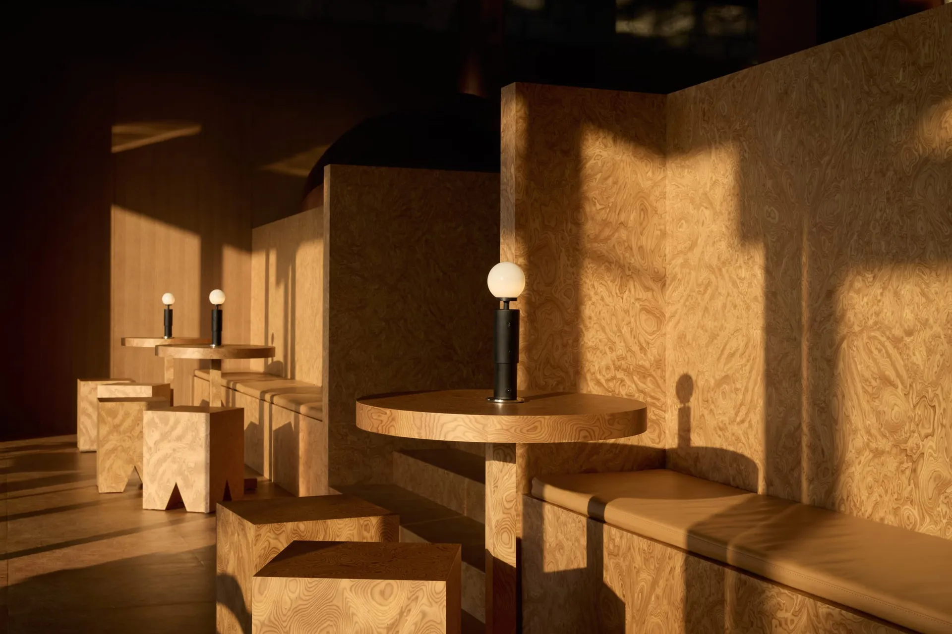 Warm and inviting indoor space with wooden walls and tables, featuring benches with lights and multiple seating options