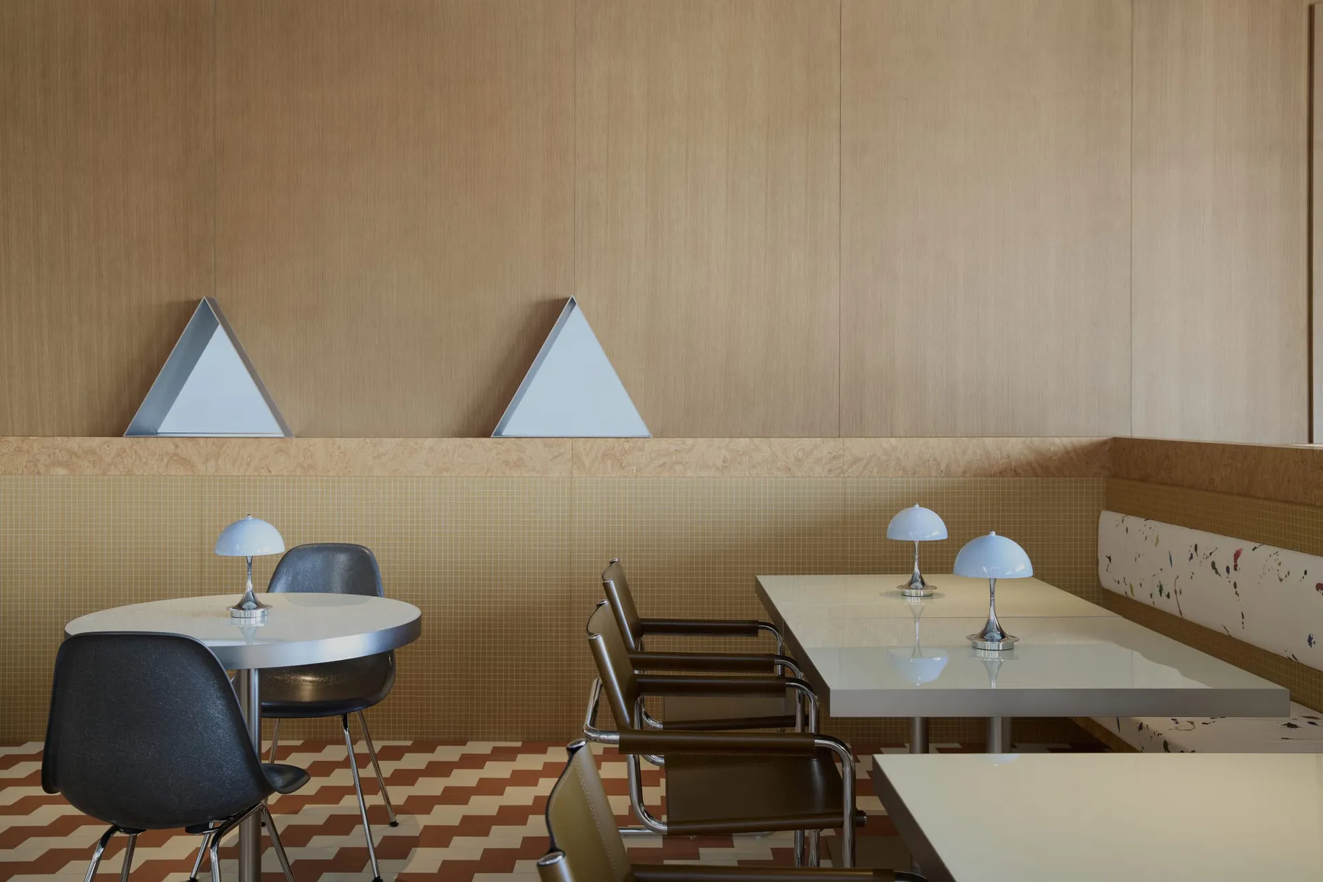 a dining area with a large table, chairs, lamps, and geometric patterns on the walls, creating a warm and inviting atmosphere