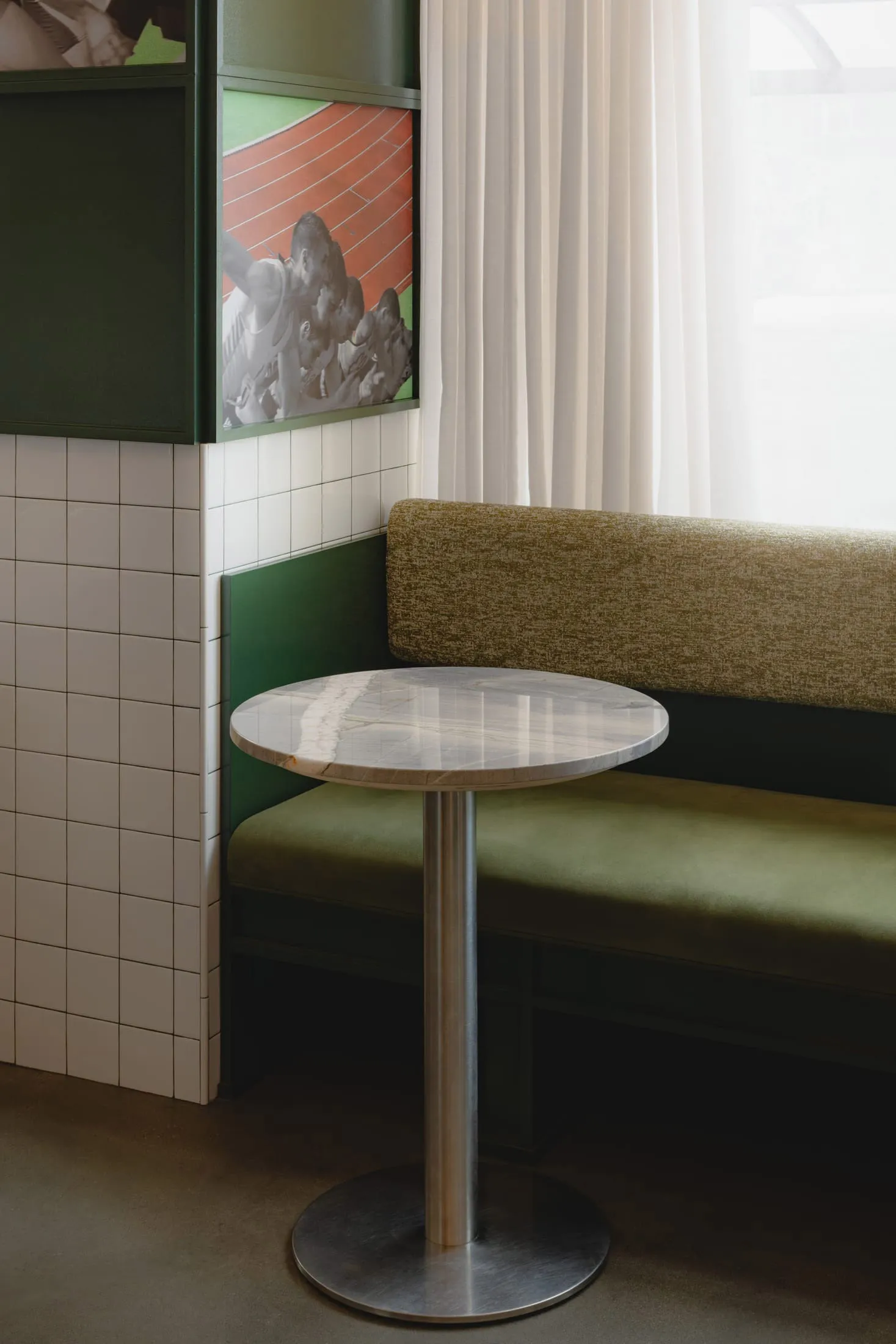 A cozy living space with a green metal bench, a dining table, and a vase, set against a neutral background