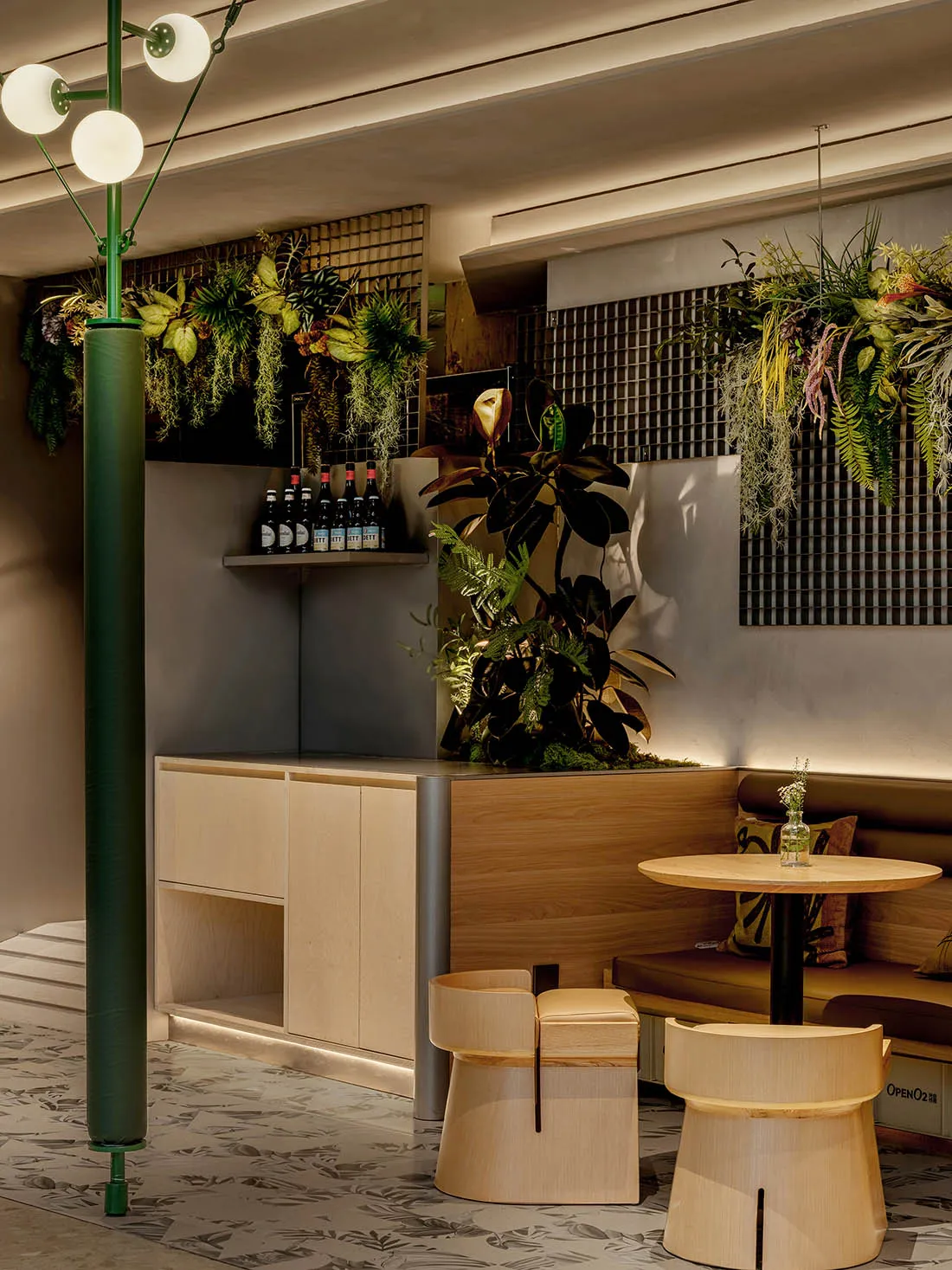 A warm and inviting cafe with a dining table, wooden elements, and multiple potted plants, creating a cozy seating area with a lively atmosphere