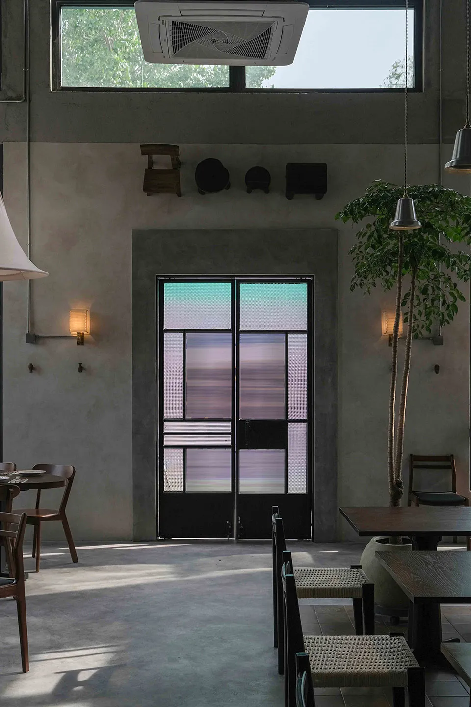 A modern cafe with a glass door, white and grey walls, and comfortable seating areas with chairs and dining tables