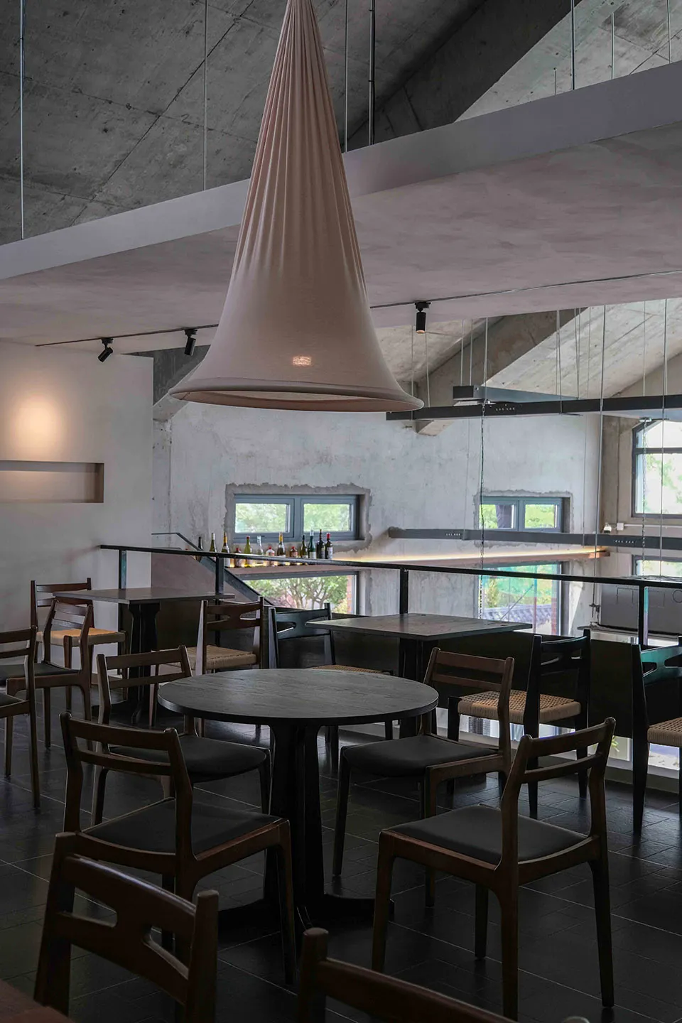 現代餐廳空間配有多張餐桌與椅子，各種表面上擺放四瓶酒瓶，營造時尚氛圍