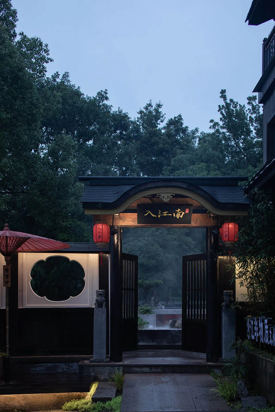 Traditional Asian entrance with a wooden structure and red roof, featuring two people standing near the doorway