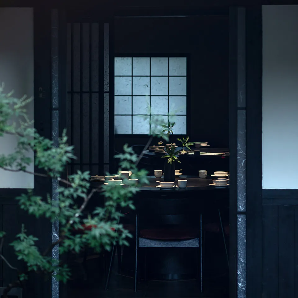 黑白主題亞洲餐廳內部，設有餐桌、椅子與盆栽，營造溫馨舒適的氛圍