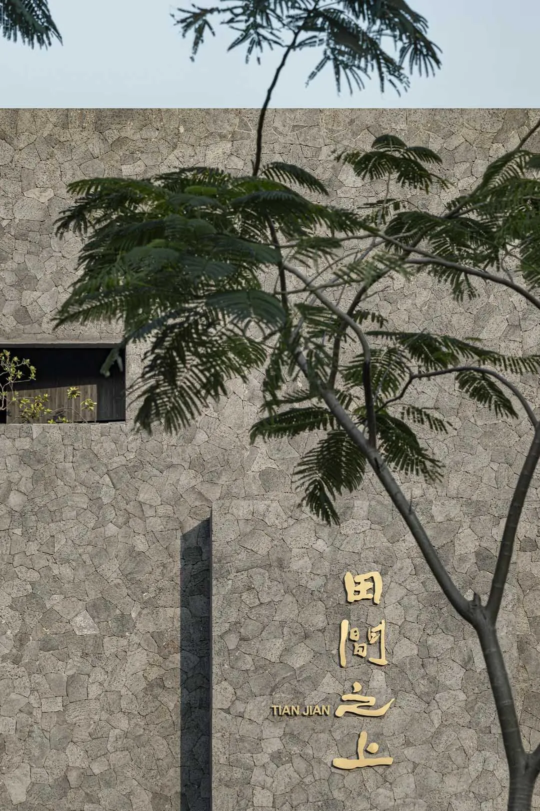 亞洲風建築，石材外牆，前方兩棵樹，牆上有中文書法