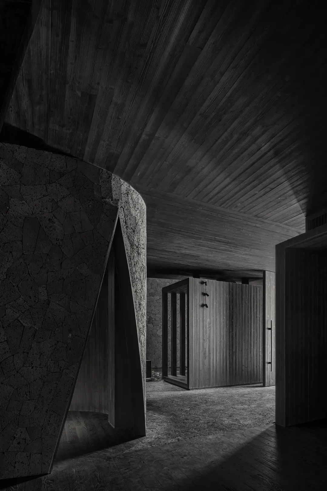 A dimly lit hallway with stone walls, featuring two darkened rooms with doors on either side