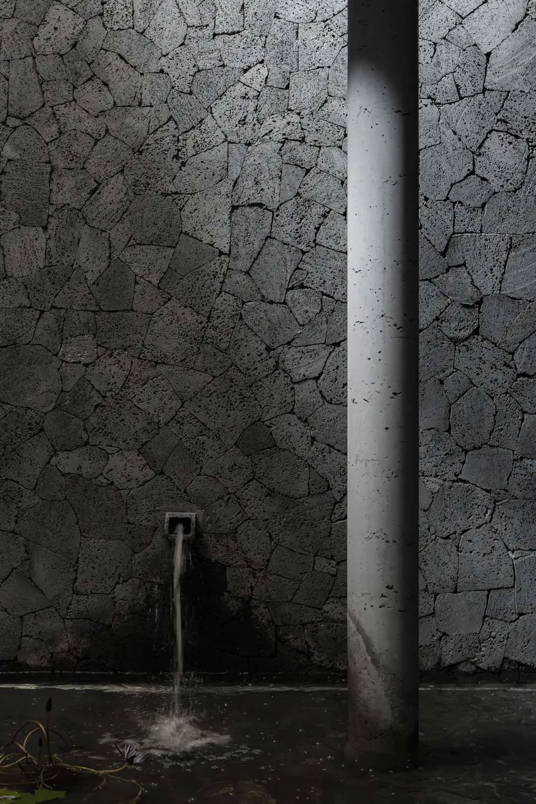 Aged stone wall with cement brick texture and two exposed pipes, one on each side, conveying a sense of history and craftsmanship