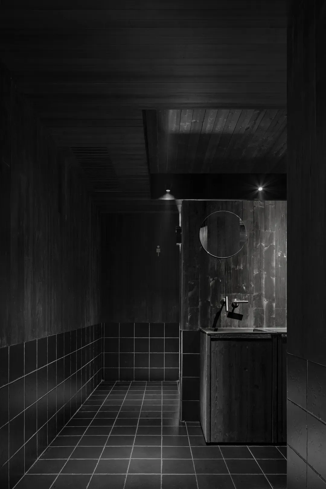 A minimalist bathroom with two sinks, a shower stall, and a mirror above the sink area, set against a neutral background