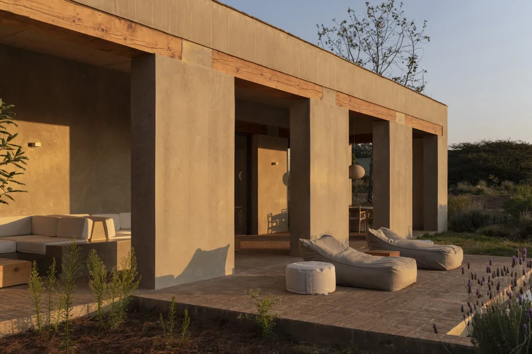 A stone-walled outdoor patio with a concrete floor, featuring multiple chairs and couches, creating a relaxed and inviting atmosphere