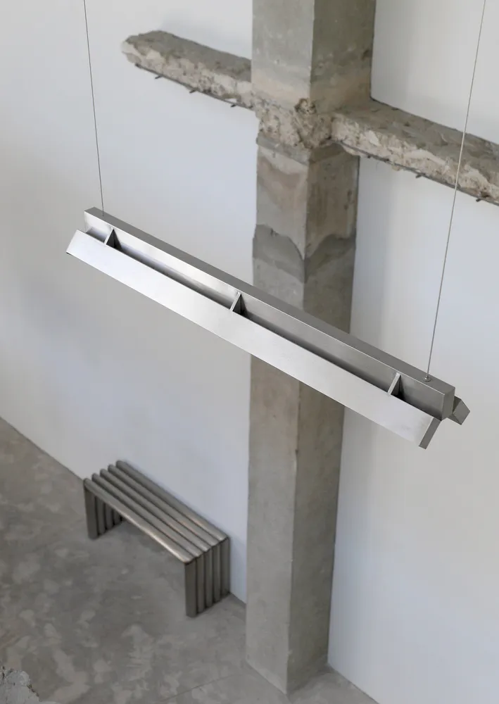 Industrial space with a metal beam, two benches, and a chair, featuring a functional and utilitarian atmosphere