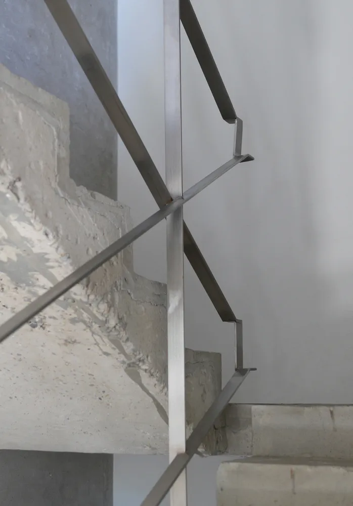 A modern staircase with metal stairs and a concrete wall in a building's interior, suggesting a functional yet stylish design element