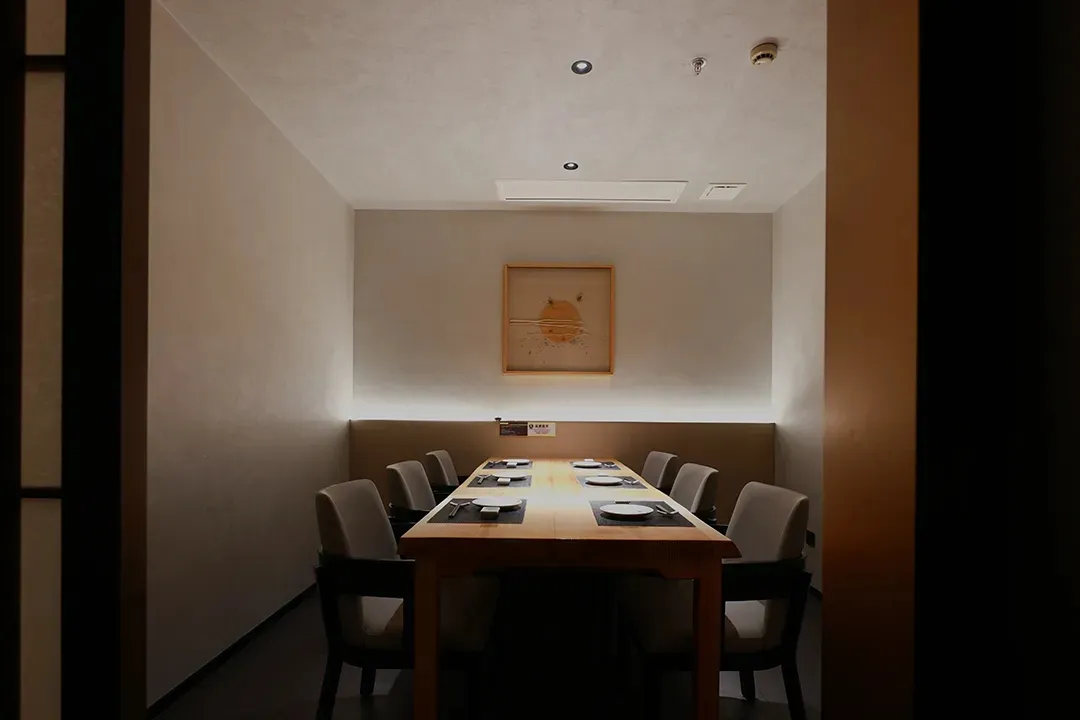 A well-lit and inviting restaurant dining area with a long wooden table surrounded by multiple chairs, creating a calm atmosphere for guests to enjoy their meals