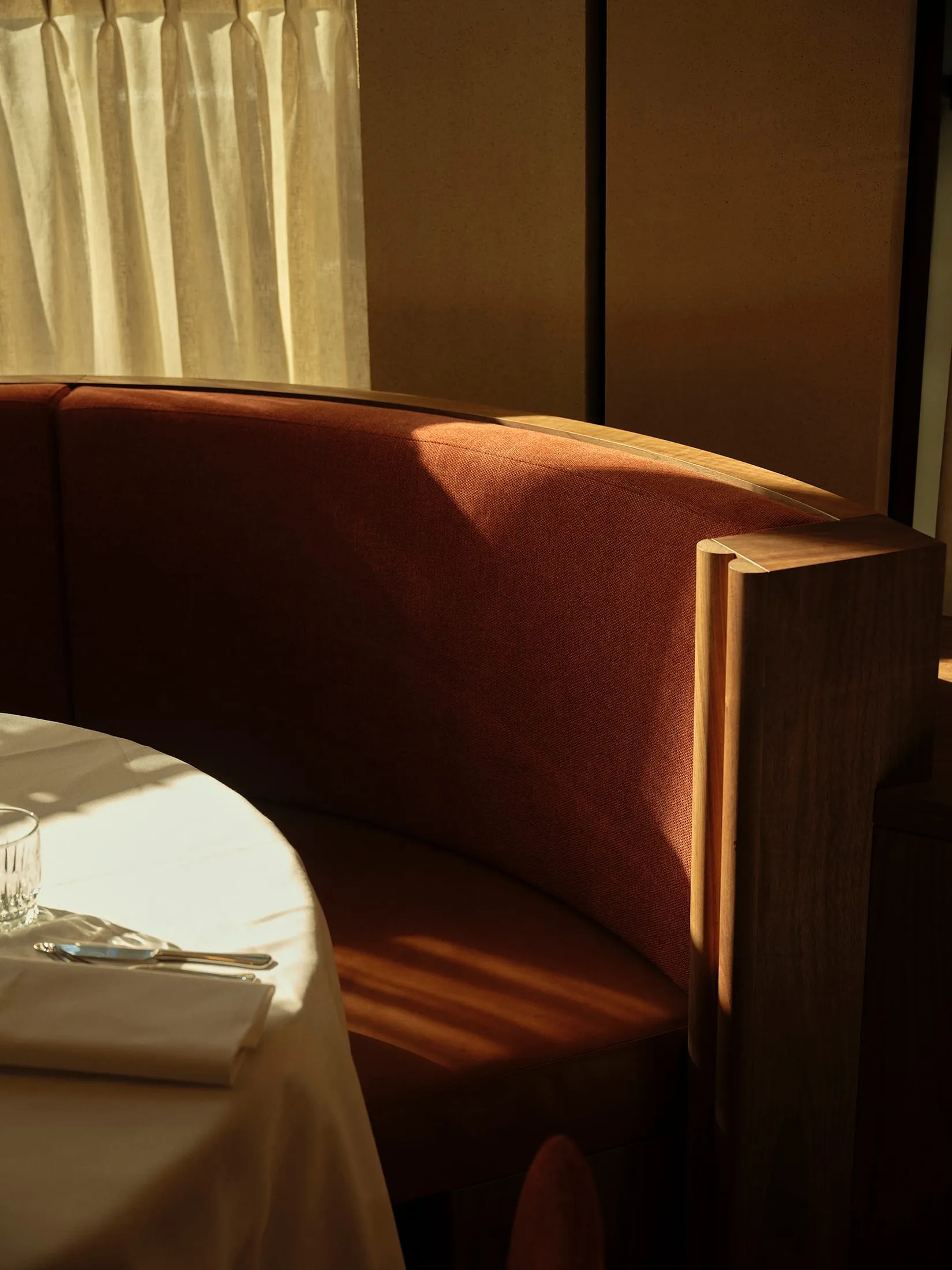 A warm and inviting dining area with a red couch, a table, and two chairs, featuring a wine glass on the table