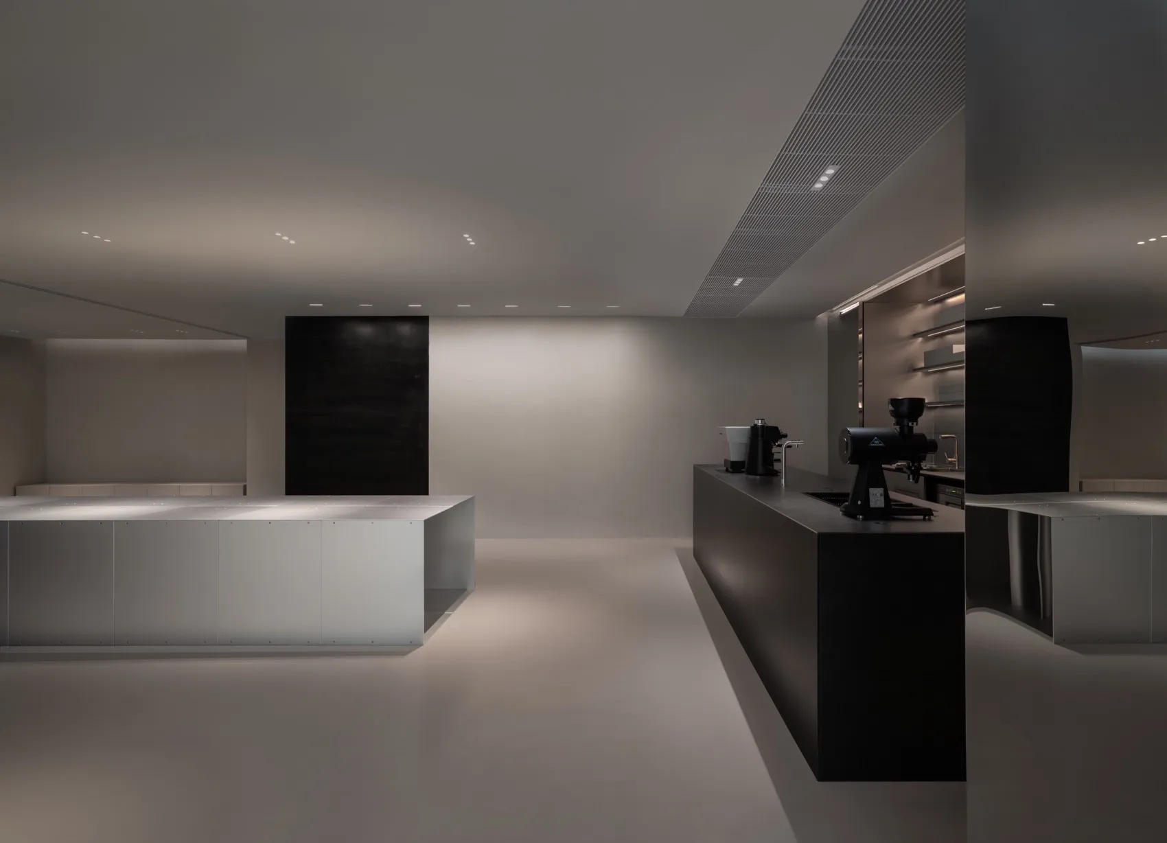 Commercial kitchen with white walls and floors, featuring modern appliances and minimalistic design
