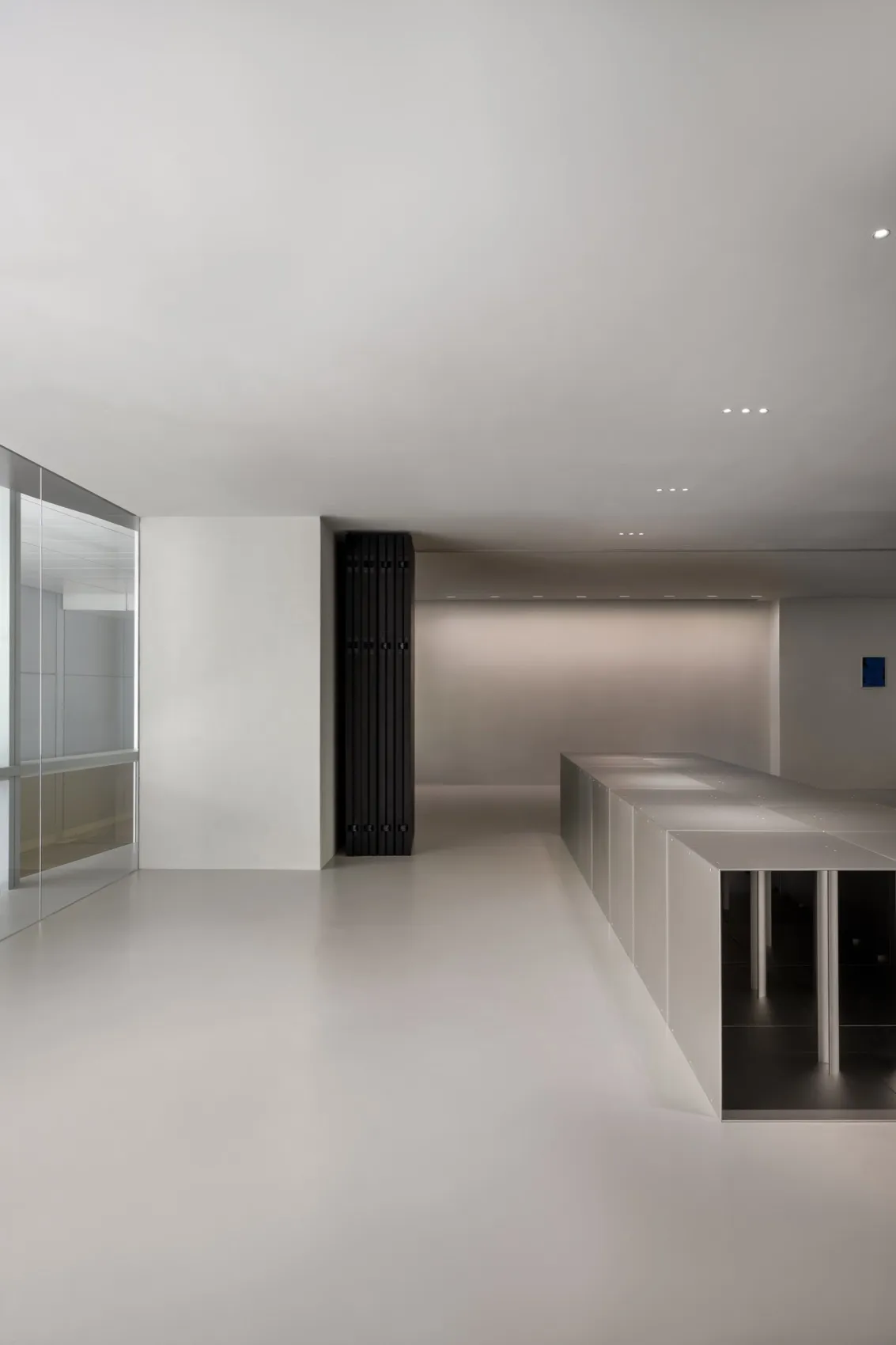 A clean and minimalist lobby with white walls, a large window, and an empty space