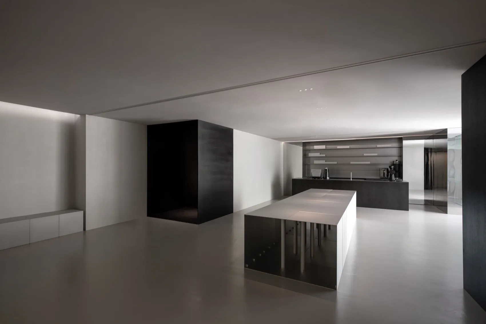 Empty modern kitchen with white walls and floors, featuring a dining table, chairs, and a sink
