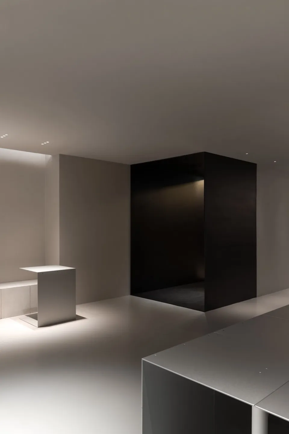 Dimly lit room with a black doorway, two white tables, and a mysterious atmosphere