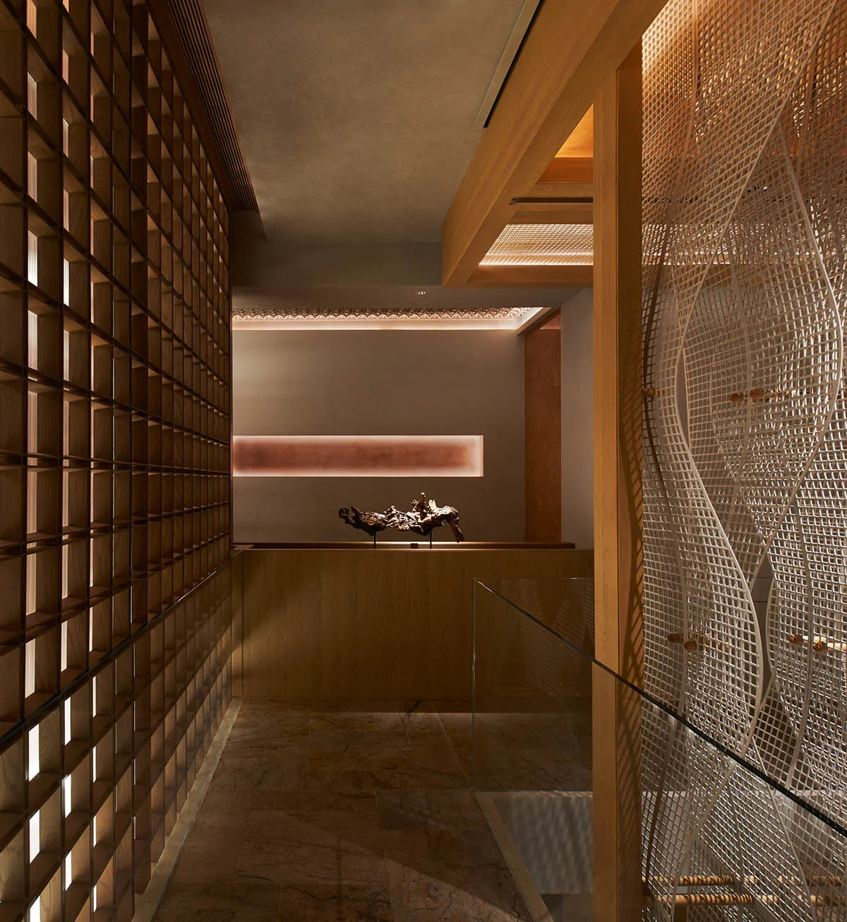 A modern hallway with a glass partition separating two rooms, featuring a wooden floor and natural light from windows on both sides