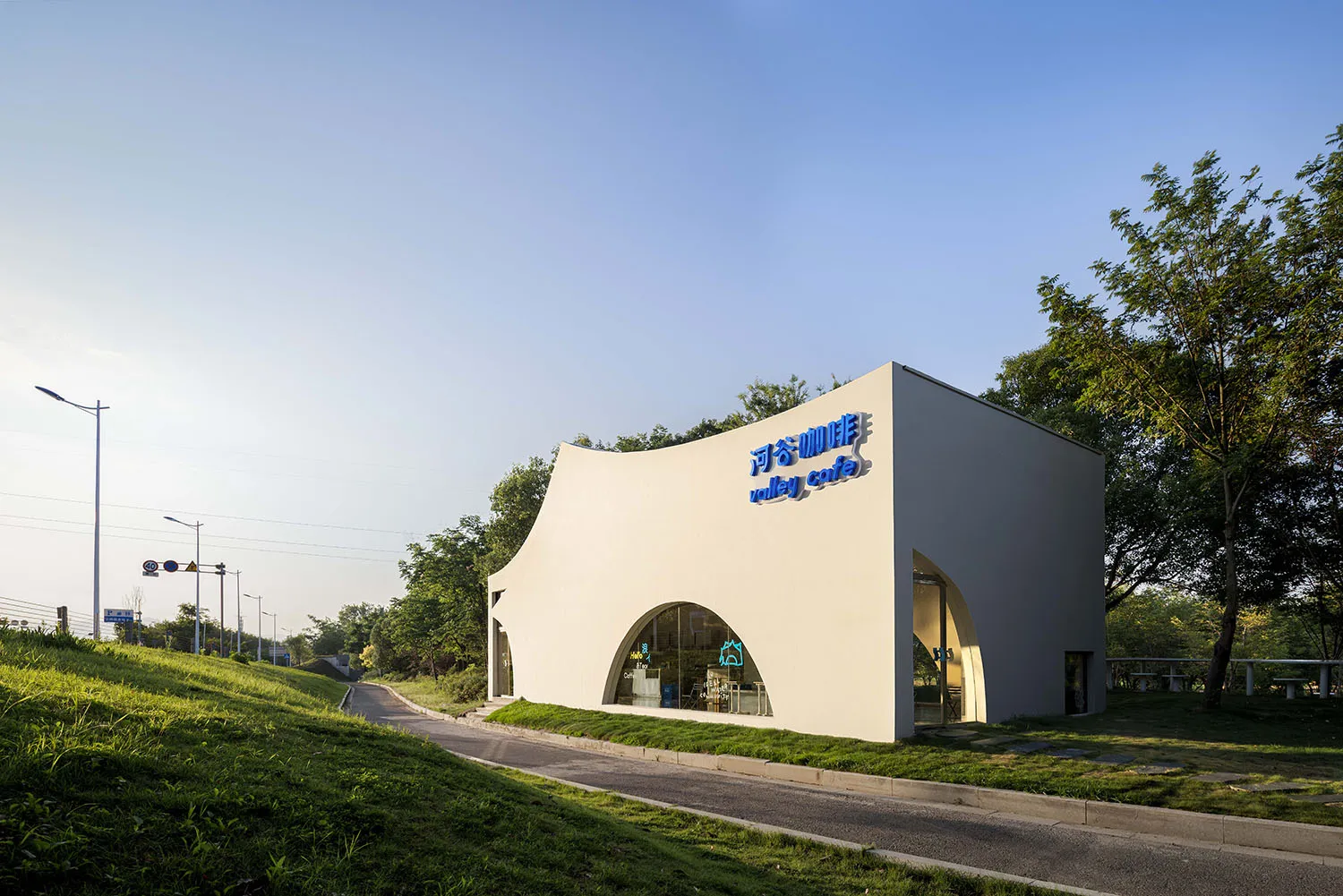 A modern building with a white concrete facade, featuring a large circular window and smaller windows, giving off a minimalist vibe
