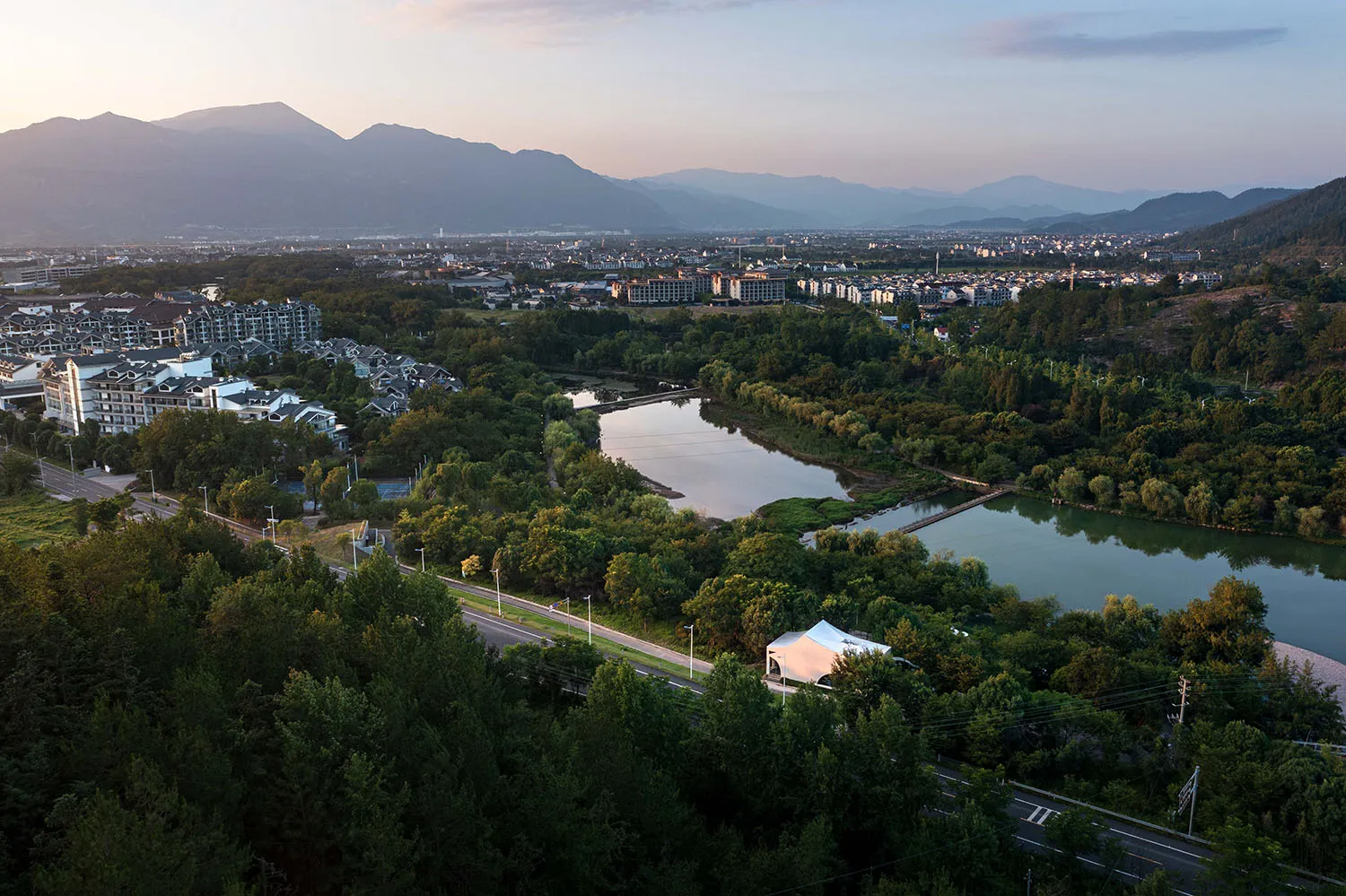 A serene cityscape with a large body of water in front of a building, surrounded by multiple structures with a calm atmosphere