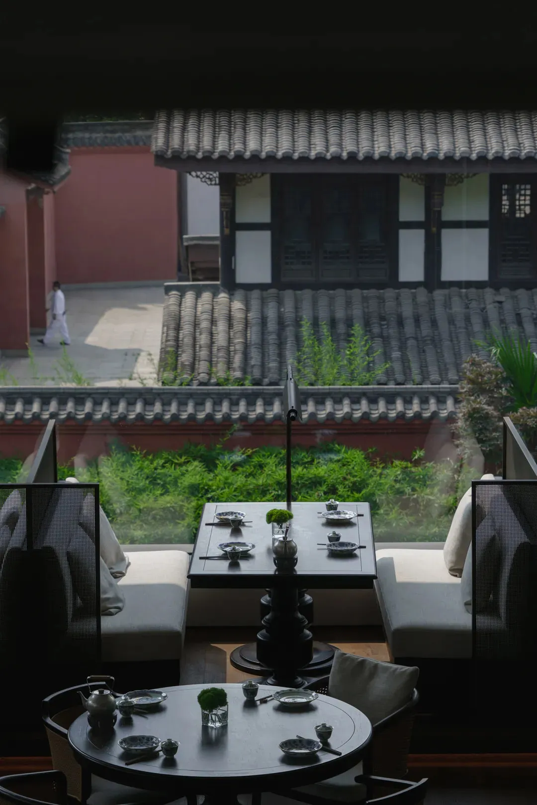 Cozy Asian restaurant with a large dining table, red wall, and tiled roof, set up for a meal