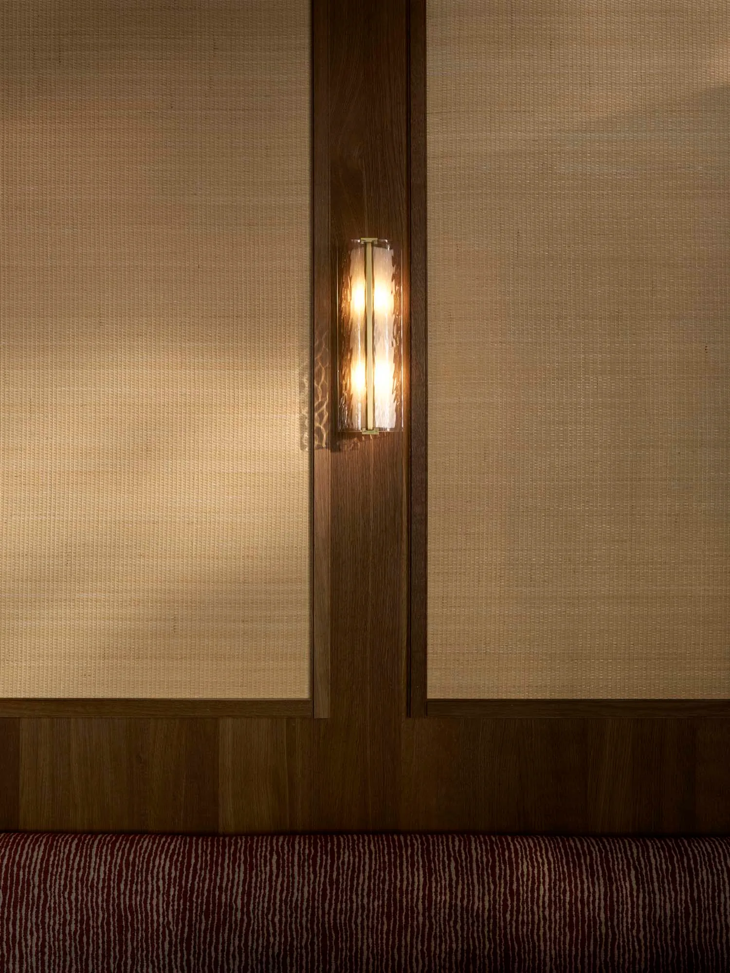 Warm living space with wood paneling, a wooden door, and a cozy couch, lit by a small lamp and another light source