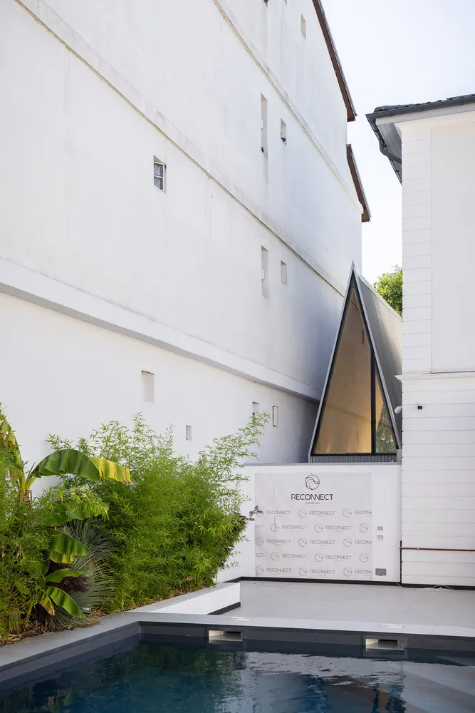 A modern building with a large white wall featuring two windows, one large and one small, made of concrete with a sturdy and solid appearance