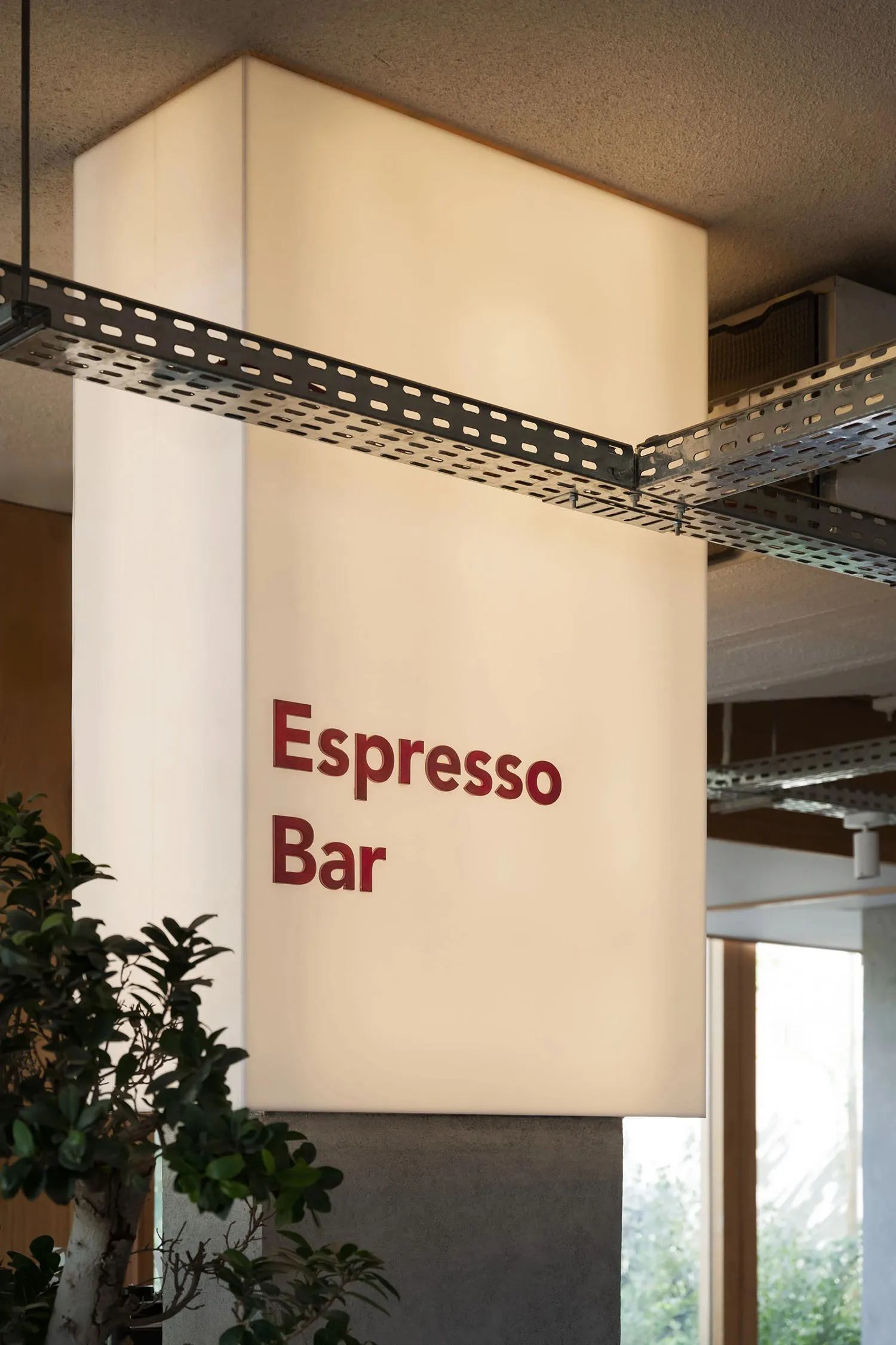 溫馨酒吧內部，紅色「Espresso Bar」招牌、白牆面，以及兩盆綠植增添綠意