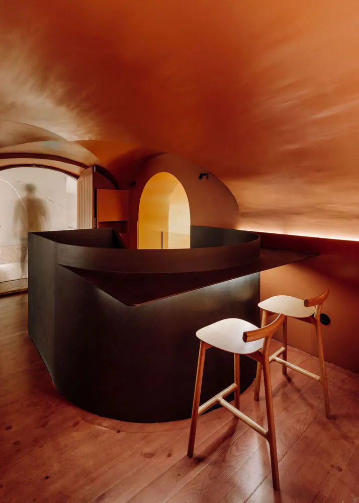 A warm and inviting bar area with a modern wooden or metal bar, two stools, and a focus on creating a comfortable social space
