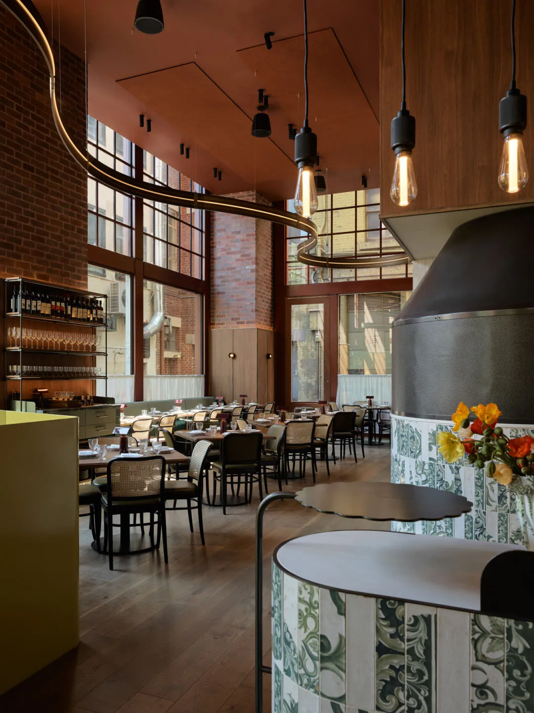 Warm dining space with wooden flooring, brick walls, and tables set with wine glasses, conveying a welcoming atmosphere for food and drink