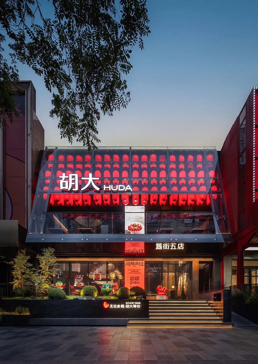 A modern Asian storefront at night with a glass front, featuring comfortable seating and a stylish interior