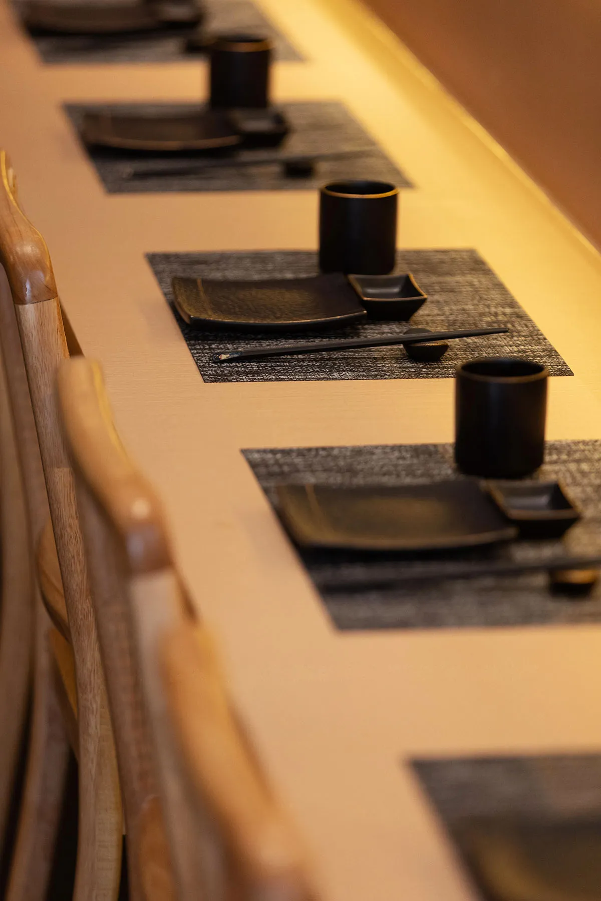 A formal dining area with a long table set for a meal, featuring black tableware and multiple chairs, creating an inviting atmosphere for guests