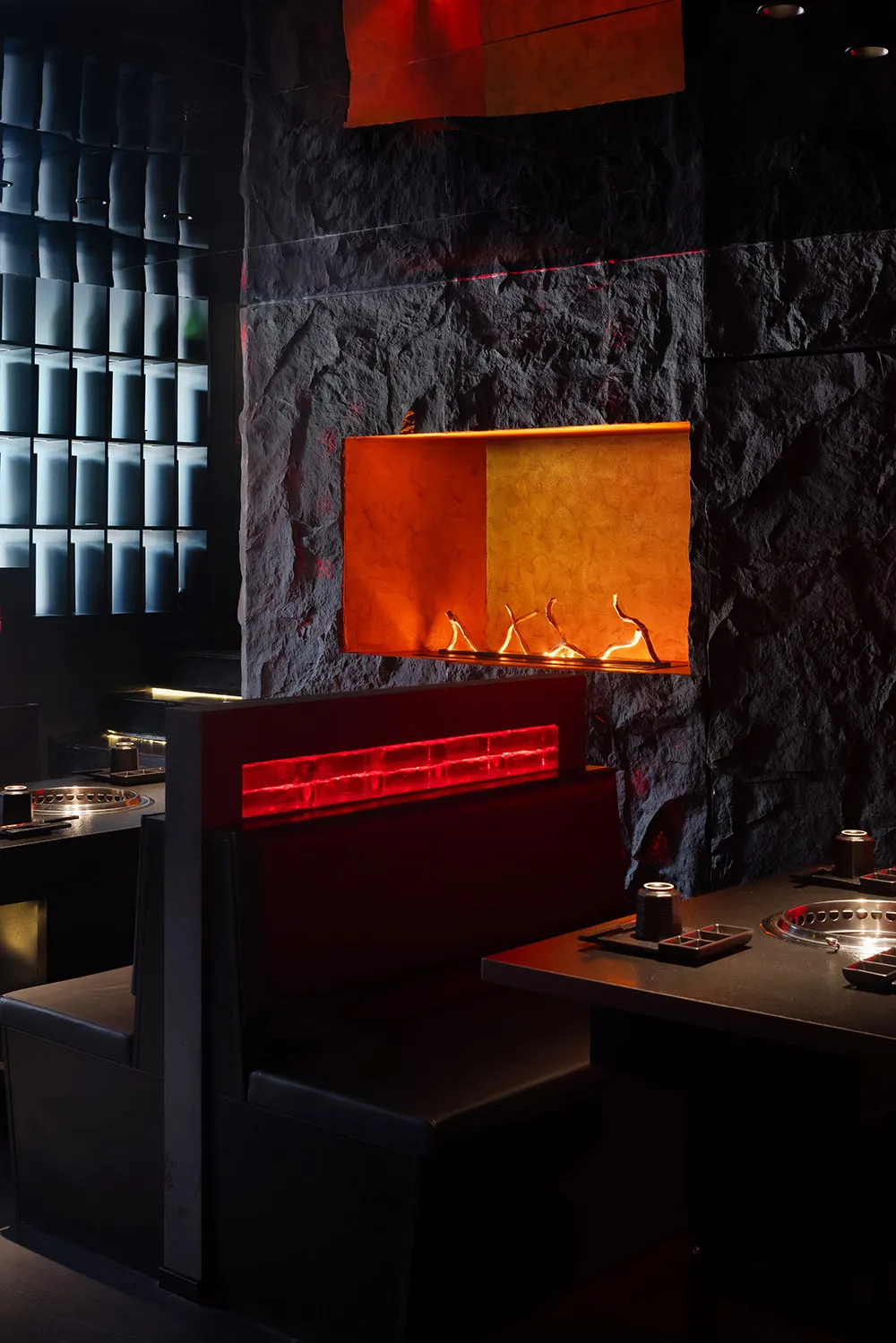 Warm and inviting restaurant interior with a stone wall, fireplace, and dining tables and chairs