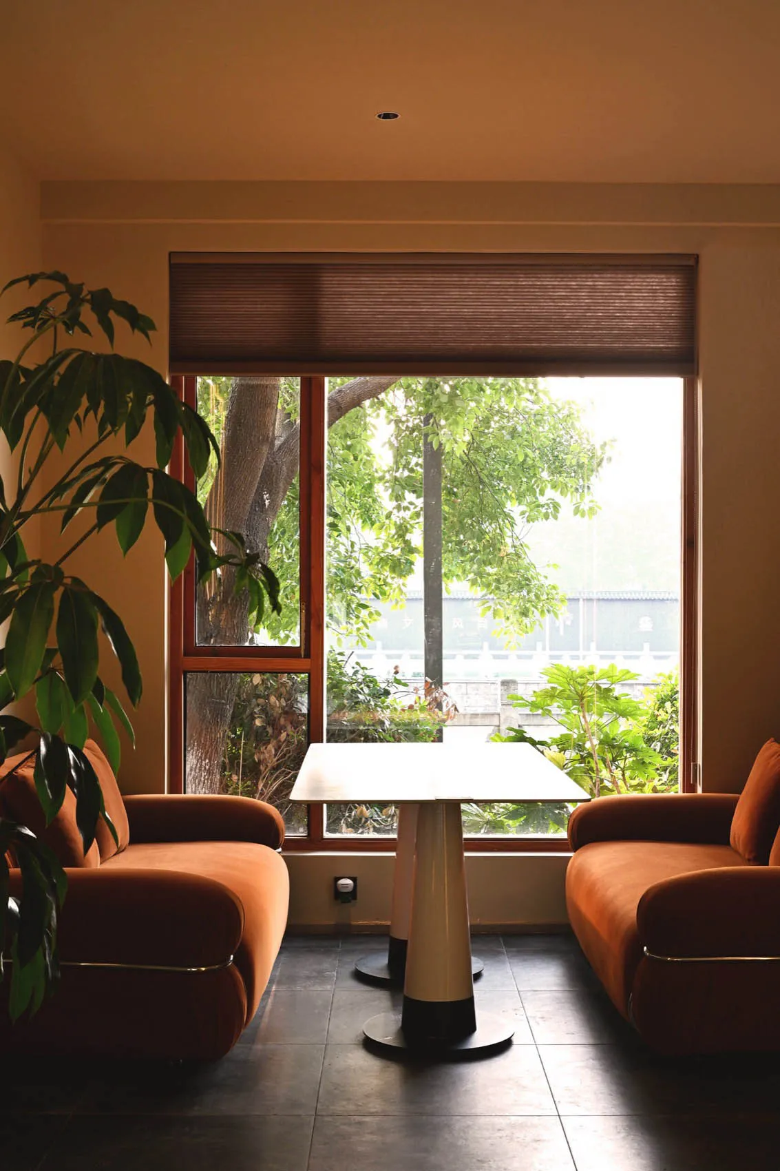 A well-lit living area with two brown chairs and a dining table near a large window, creating a cozy seating arrangement